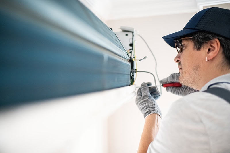 A technician performing maintenance or an installation on an indoor air conditioning unit.