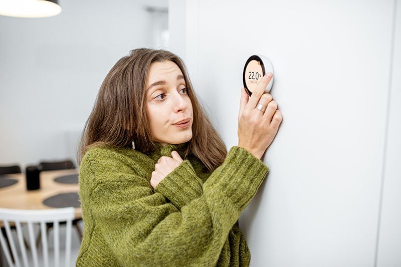 Why Is My Heat Pump Turning On and Off Frequently? - Woman Adjusting Her Thermostat.